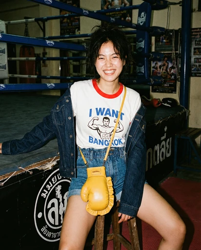 Smiling woman with a yellow boxing-glove bag in a gym