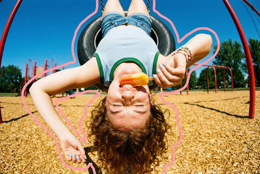 Upside-down girl on a tire swing in a playground